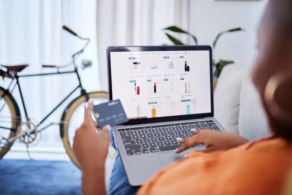 Eine Person kauft online mit einem Laptop ein und hält eine Kreditkarte in der Hand.